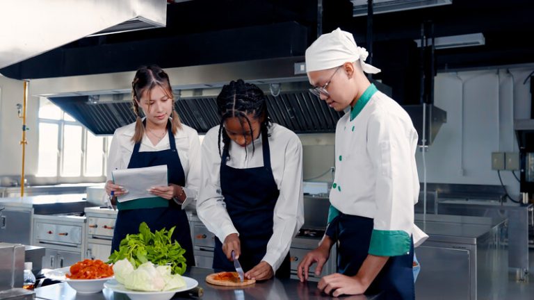 Tre elever från Restaurang- och livsmedelsprogrammet står i kök och lagar mat.