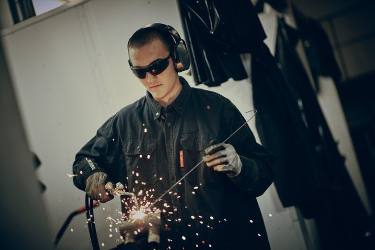 Elev på Yrkesgymnasiet svetsar med skyddsglasögon och hörselskydd under praktisk utbildning.