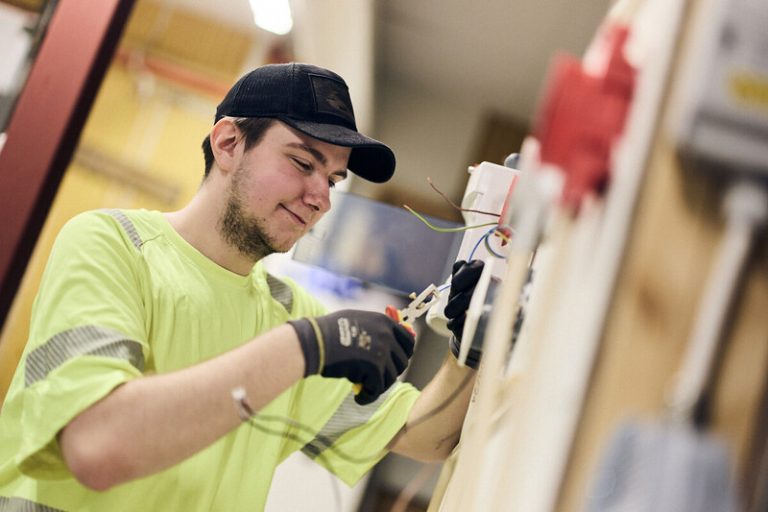 Elev från El- och energiprogrammet kopplar el i vägguttag under praktiskt övningsmoment.