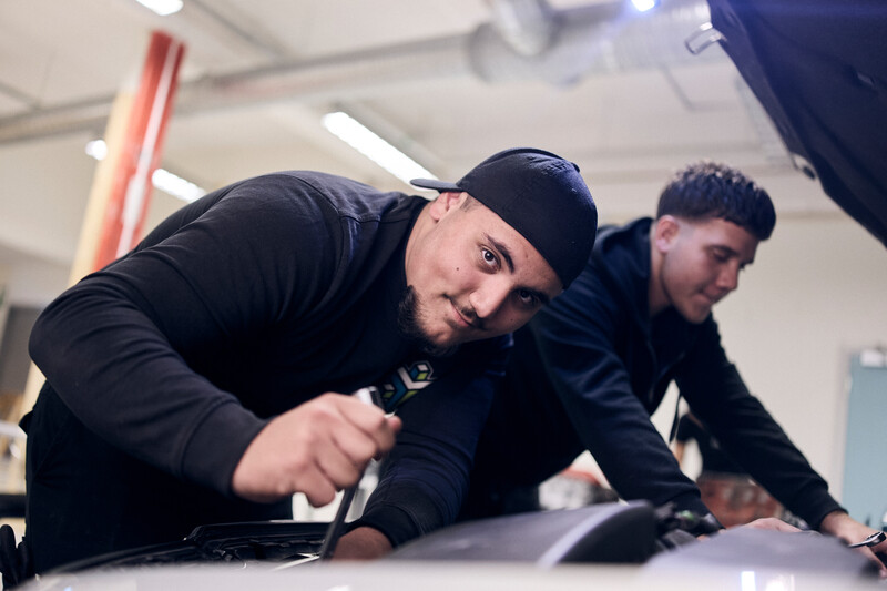 Elever står framför motorhuv och meckar med bilen.