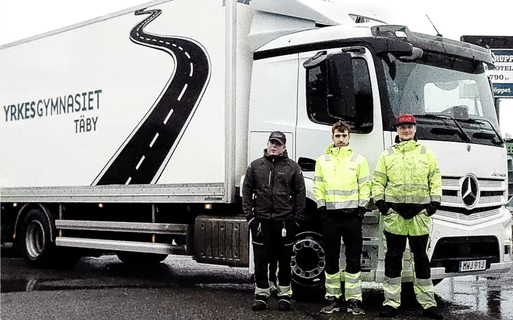 Tre killar står framför lastbil.