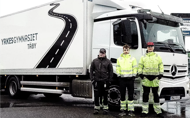 Tre killar står framför lastbil.