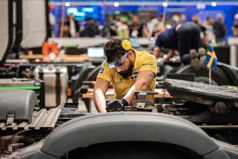 En lärare arbetar fokuserat med en lastbil under en tävling.