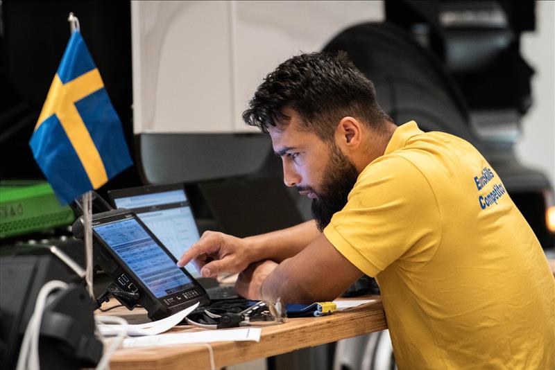 En elev analyserar data vid en dator med en svensk flagga på bordet.