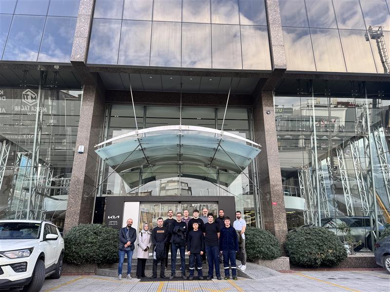 Grupp människor poserar framför en modern glasfasad vid en byggnadsentré.